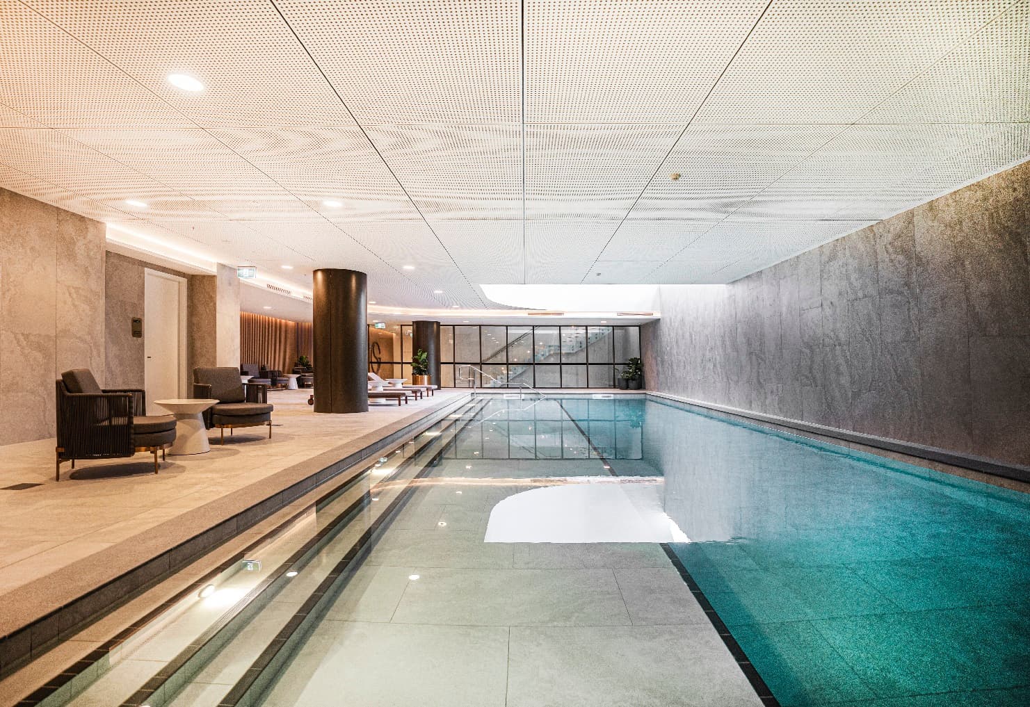 A large residential tower swimming pool with deck seating and marble walls