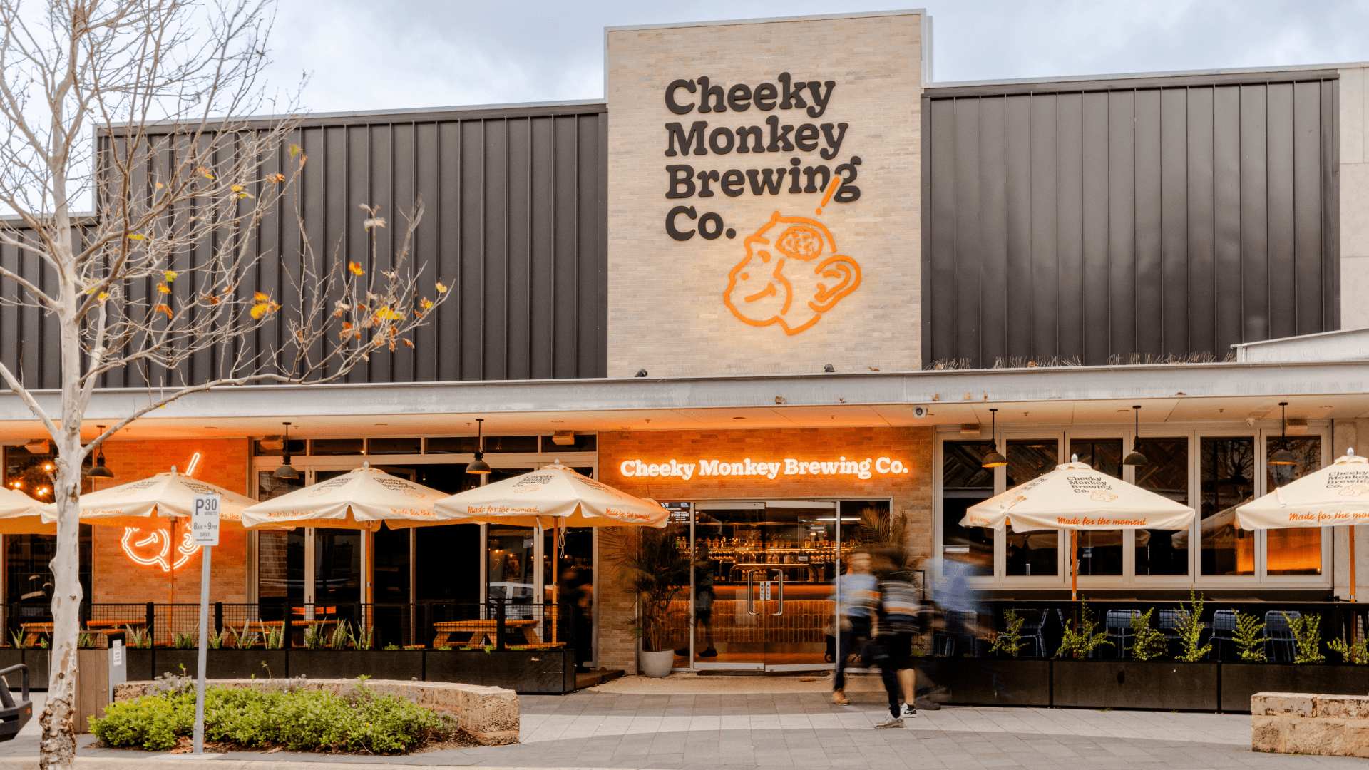 Brewery entrance with umbrella, plants and a large monkey sign above the door