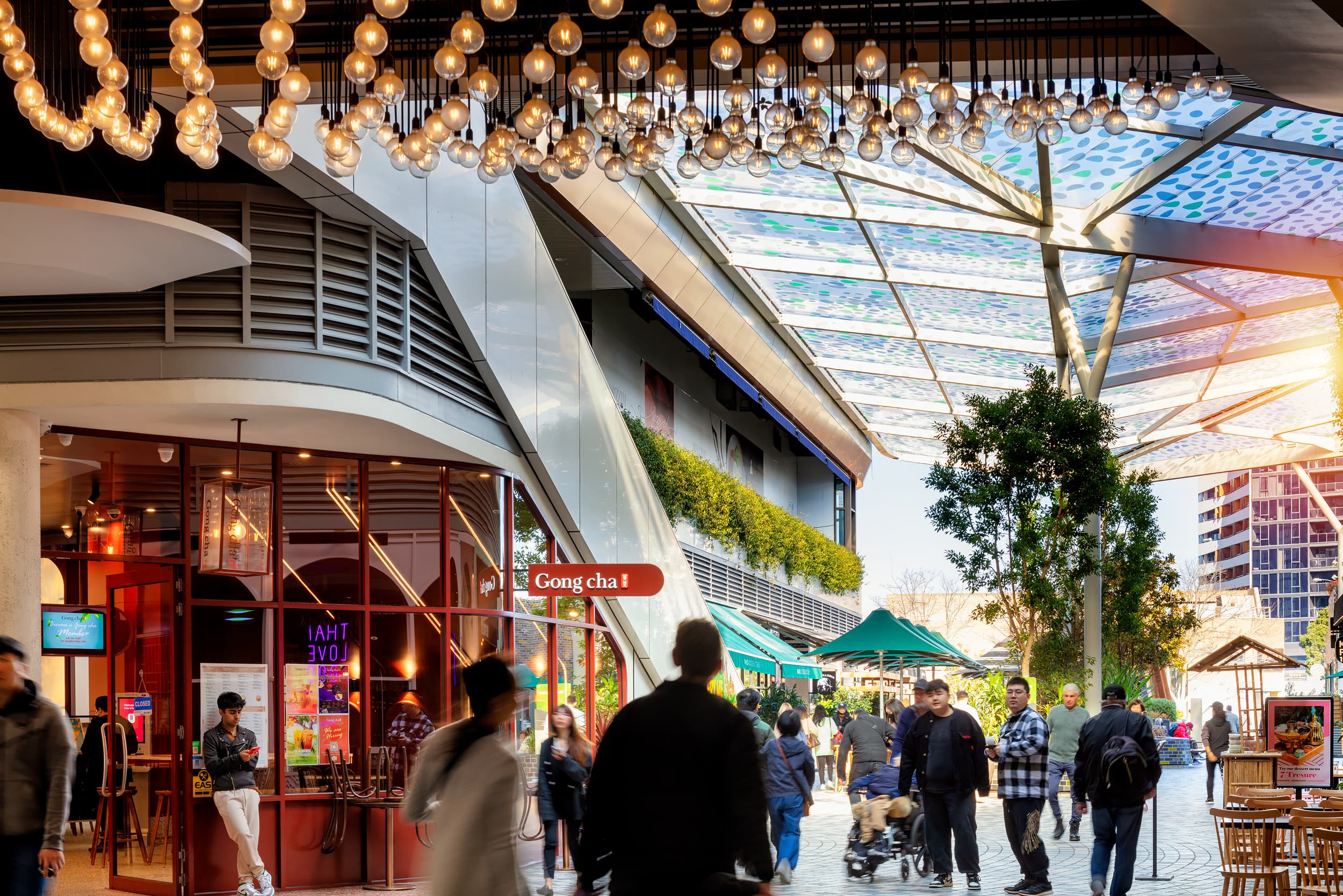 A busy retail precinct with covered roof and sunlight shining through