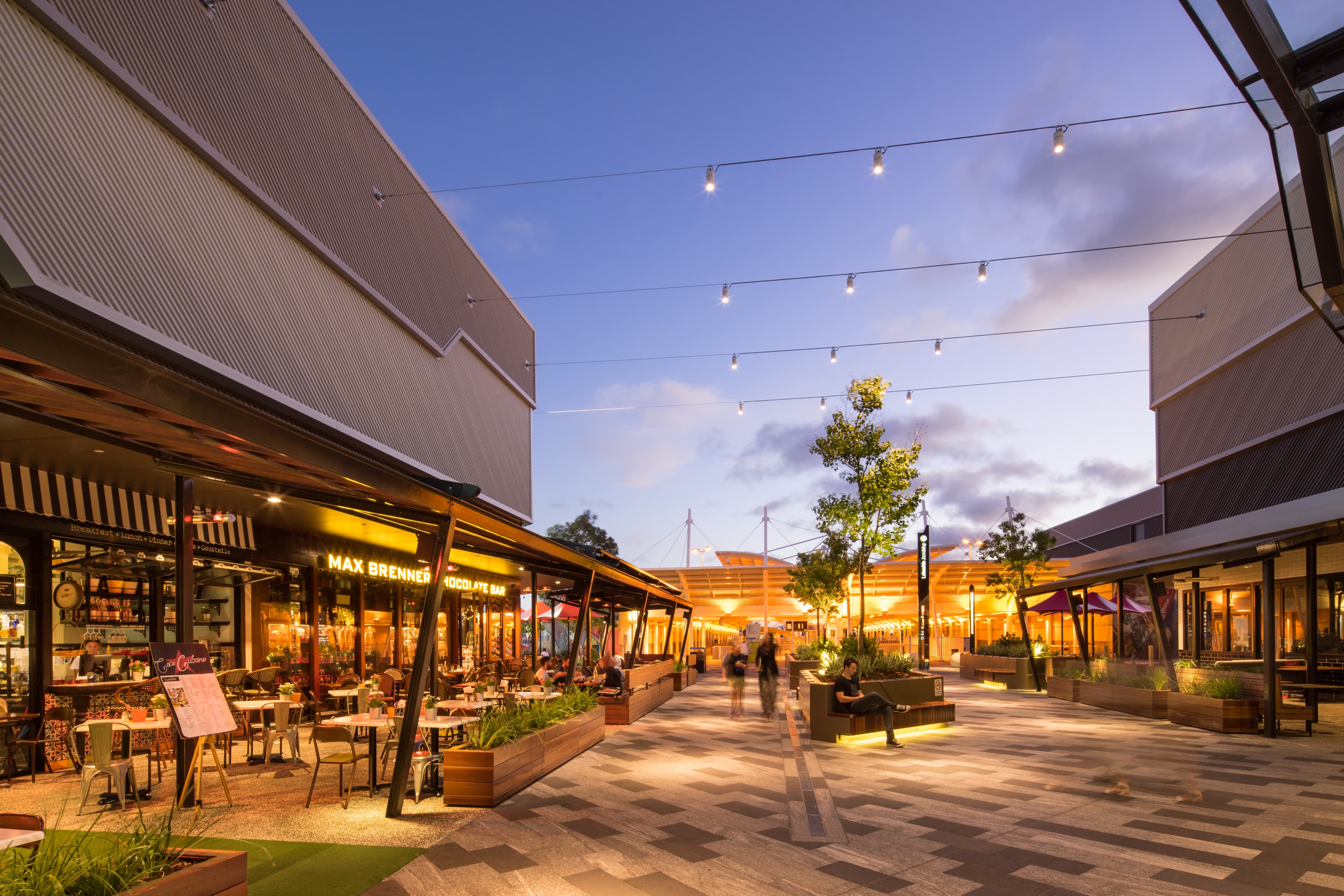 Outdoor dining and walkway at a shopping centre at twilight